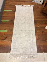Full view of ivory and gray runner rug with fringe