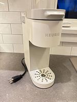 Front view of white Keurig coffee maker with cord
