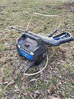 Pressure washer with wand and hoses on ground