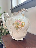 Front view of ornate porcelain pitcher showing floral transfers and gilt accents