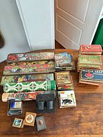 Overview of lot showing decorative slide-top boxes, branded cardboard boxes, tin cylinder and smaller pieces