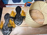 Two black metal double wall sconces with amber glass shades and beige drum lampshade on wooden surface