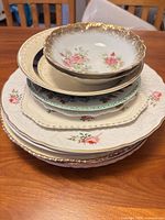 Stack of assorted vintage plates and bowl showing varying patterns and sizes