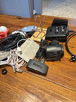 Pile showing Roku adapter, charging dock, phone stand, cables, chargers