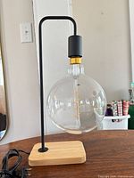 Front view of table lamp showing bamboo base, metal rod, globe bulb, plug