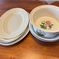 Stacked oval Edme platters, round floral platters and open casserole on table