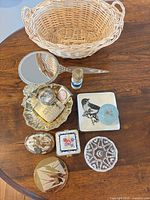All items arranged on tabletop including basket, mirror, tray, compacts, dishes, jars, brush