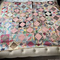 Full view of multi-coloured patchwork quilt spread on bed