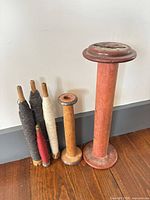 Six assorted wooden bobbins/spools lined up showing relative sizes and yarn colors