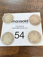 Four coins reverse side showing maple wreath design and heavy wear