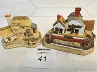 Two David Winter cottages on counter with lot card