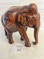 Front-right view of polished wooden elephant figurine showing head, trunk, ear, body grain