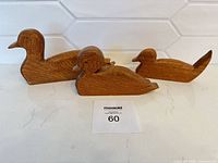 Three wooden duck figurines side by side