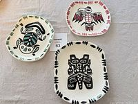 Three plates displayed on cloth surface with measurement tag