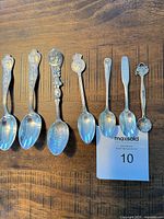 All seven teaspoons laid out bowls down showing ornate handles