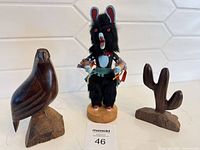 Kachina doll flanked by carved bird and cactus figures