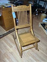 Front view of solid wood folding rocking chair showing slat back and carved crest
