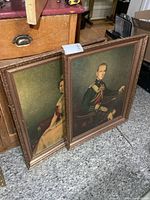 Both framed portraits leaning against cabinet