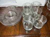 Six etched tumblers stacked beside six matching small plates