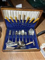 Open chest showing knives in lid, flatware in base