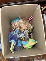 Cardboard box showing fashion dolls, Beanie Baby, sealed plush item and accessories