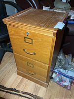 Front view showing two drawers with brass-tone handles and label frames, lock above top drawer