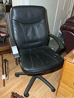 Front view of black vinyl office chair showing overall design and wear on seat