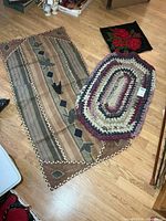 All three textile items laid out—oval rag rug, applique wall hanging, hooked panel