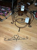 two-tier metal pie rack and separate decorative hook placed on floor