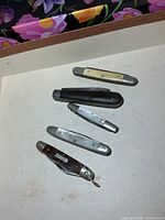 Five pocket knives laid out showing handles