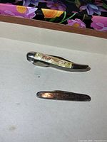 Two pocket knives, one pearloid handle, one slim metal