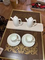 Full set displayed on table, showing tray, teapots, cups and saucers