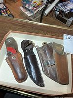 Four leather sheaths with two folding knives, overview
