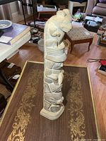 Side profile of stone totem pole showing stacked figures