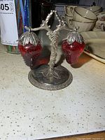 Front view of red glass strawberry shakers on silver-plate stand