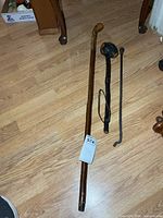 Walking stick, burled club and metal rod laid out on floor