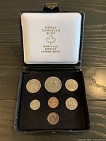 Open presentation case showing seven uncirculated 1975 Canadian coins arranged in flocked tray and Royal Canadian Mint logo on white satin lid