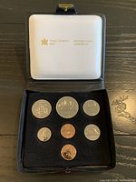 Open presentation case showing all seven coins set in black velour insert