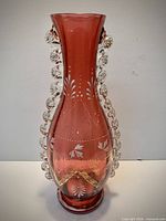 Full view of cranberry glass vase showing applied prunts, painted motifs and overall condition