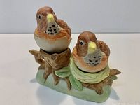 Front view of bird-shaped ceramic salt and pepper shakers seated on stump base