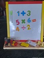 Front view of whiteboard easel with magnetic numbers and accessories on base tray