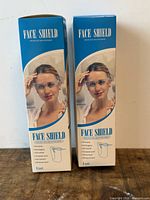 Two retail boxes labeled Face Shield Protective Isolation Mask