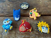 Front view of all six rubber Crocs charms on wooden surface