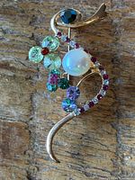 Front view of gold-tone brooch with faux pearl and multicolor rhinestones