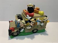 Left front view of safari truck piggy bank with Mickey, Minnie? Actually Mickey leaning out and Minnie inside? Wait disclaim; We'll state featuring Mickey, Goofy, Pluto and gorilla.