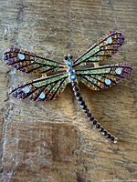 Full view of rhinestone dragonfly brooch on wood surface