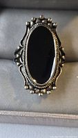 Front view of silver-tone ring with black oval cabochon