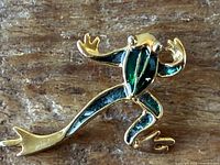 Front view of frog brooch showing gold-tone metal and green enamel