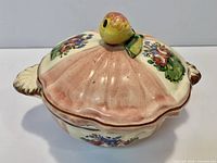 Lidded dish angled view showing floral panels and fruit knob