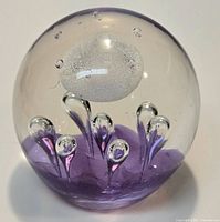 front view of clear glass paperweight showing purple plumes, white bubble and small air bubbles